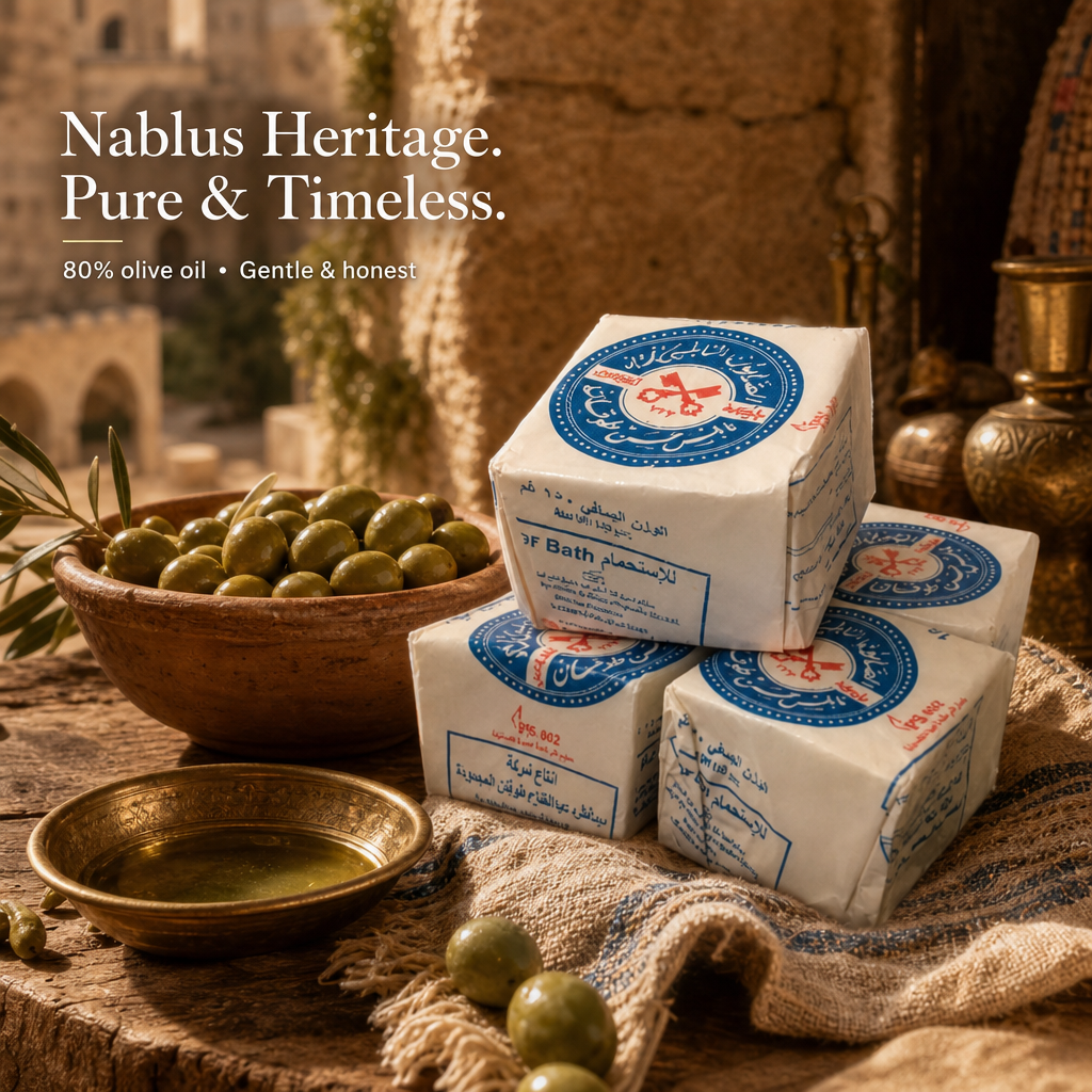 Four wrapped blocks of Nablus Heritage olive oil arranged on a rustic table beside a bowl of green olives and a small dish of oil, with warm stone background and overlaid brand text.